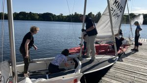 Teilnehmende des Seglertreffs Hannover takeln die Jollen am Steg nach dem Segeln gemeinsam ab.